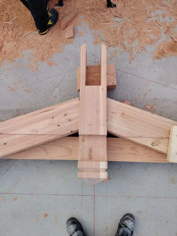 Construction d'une pièce de charpente de bois entourée de sciure.