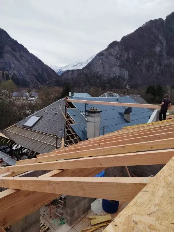 Construction d'un toit avec poutres en bois, toit bleu et fond de montagne.