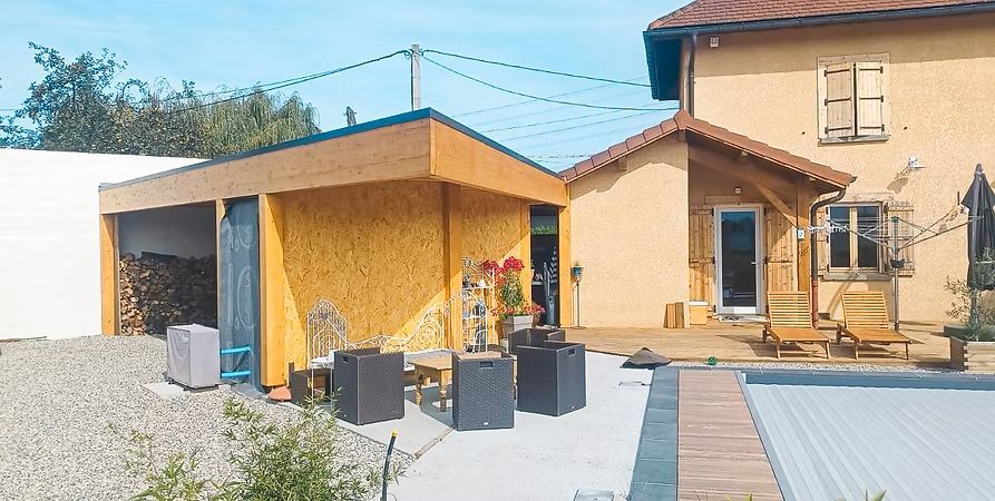 Maison beige avec ajouts en bois, terrasse et petite piscine.