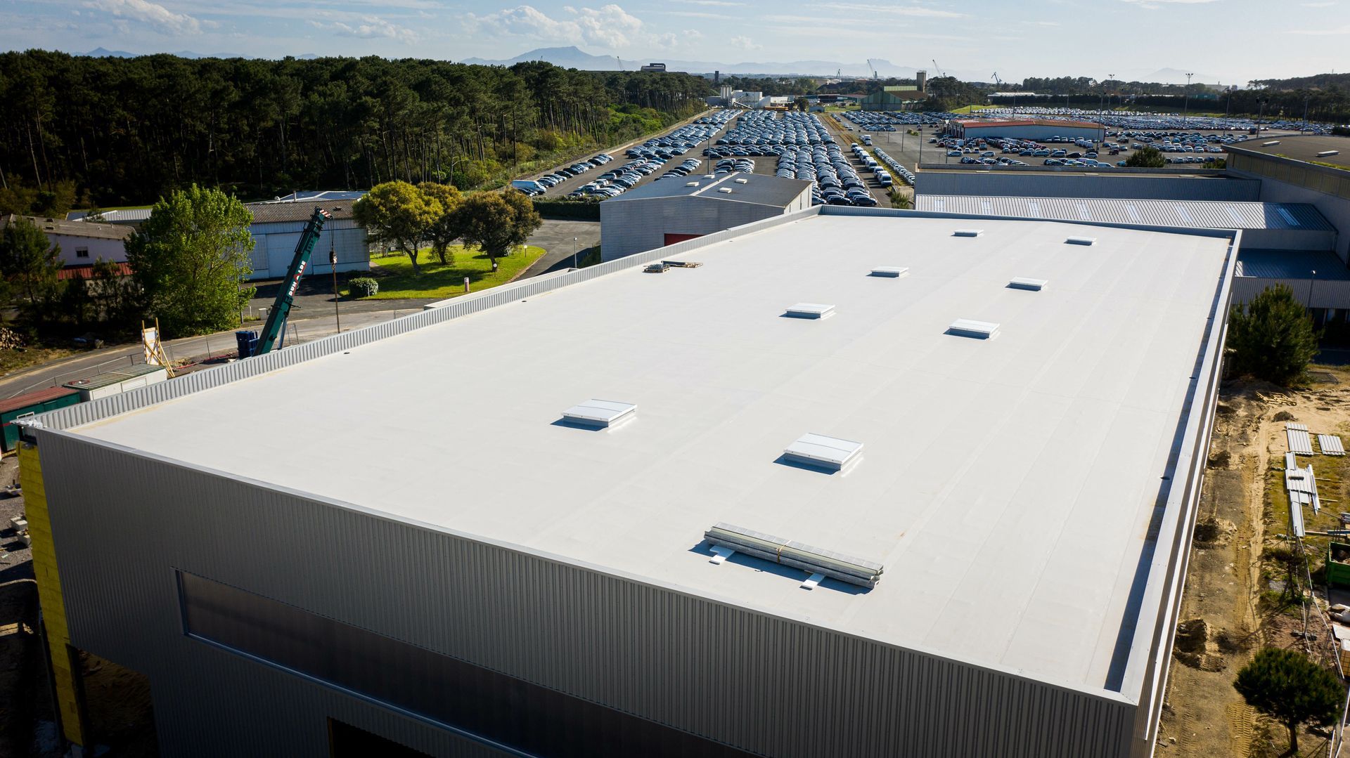Vue aérienne d'un grand bâtiment industriel avec un toit plat blanc.