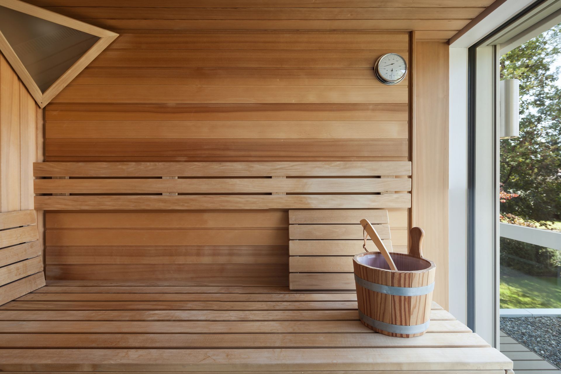 Sauna en bois avec des bancs, un seau et une horloge.