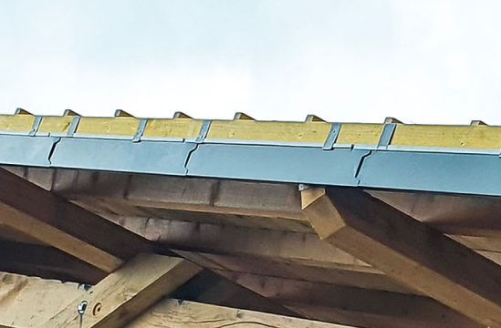 Gros plan sur le bord d'un toit avec une gouttière métallique.