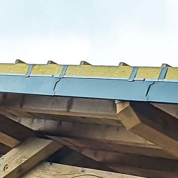 Gros plan du bord d'un toit en bois, mettant en valeur la gouttière et les poutres structurelles.