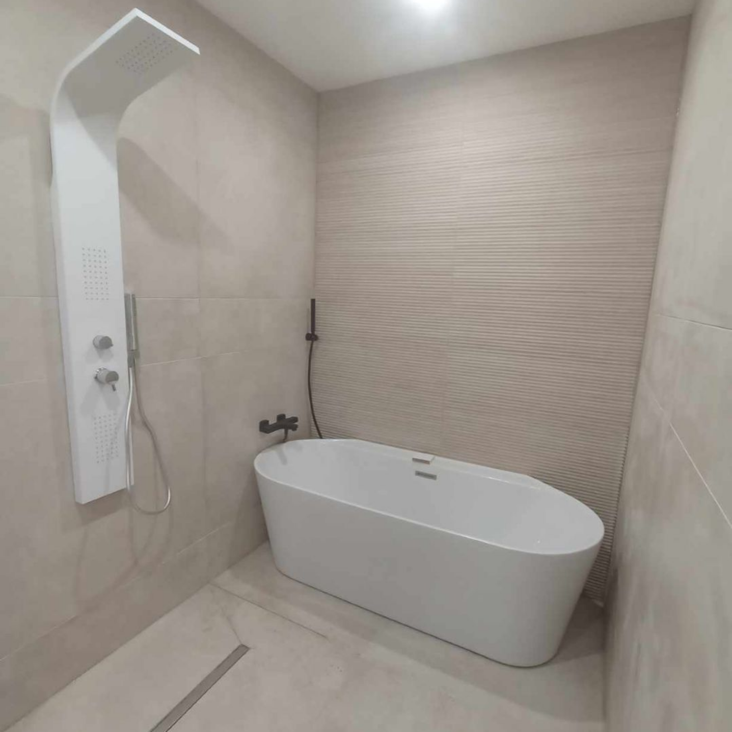 Salle de bains carrelée avec baignoire et douche