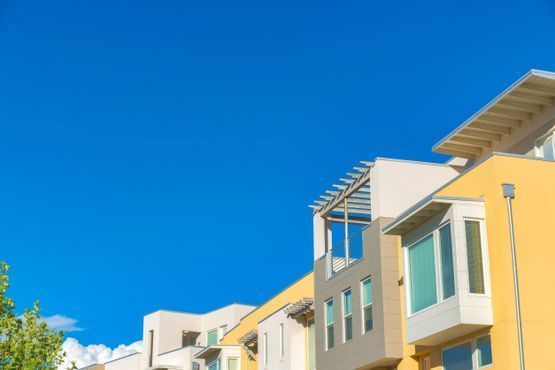 Casas adosadas de varios pisos de color amarillo y blanco contra un cielo azul brillante.