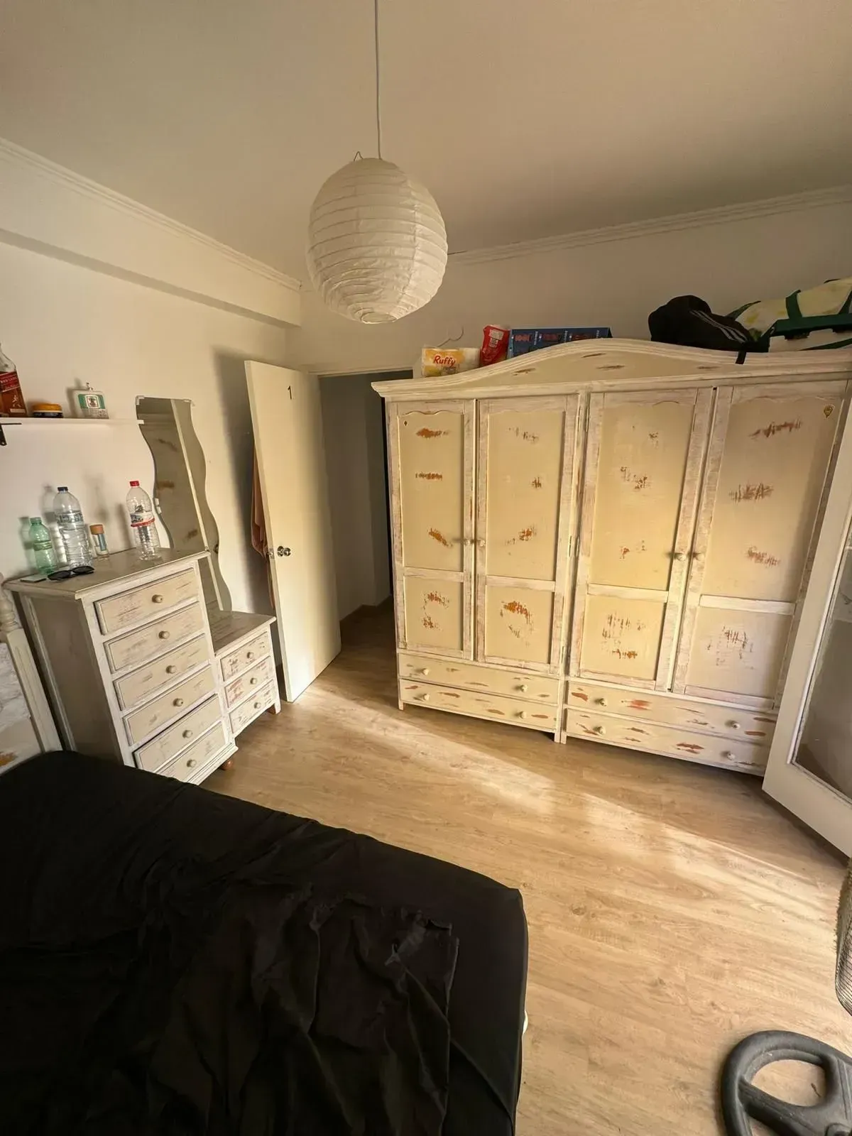 Dormitorio con cómoda blanca, gran armario, cama y farolillo de papel.