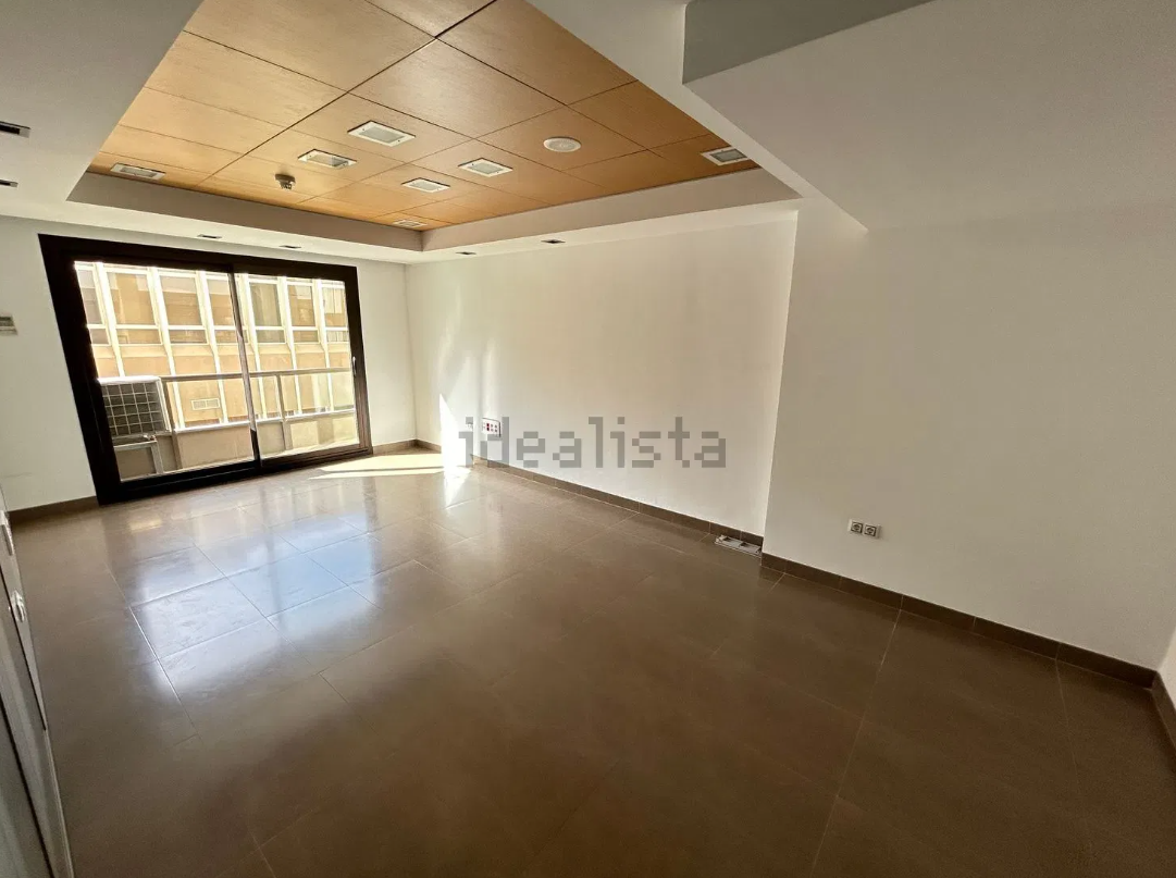 Sala de estar con sofás florales azules, mesa de centro de cristal y comedor visible al fondo.