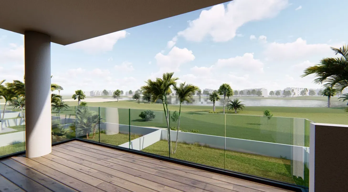 Balcón con vista a un campo de golf, con palmeras, barandillas de vidrio y un cielo azul.