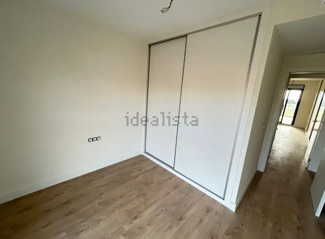 Habitación vacía con piso de madera, puertas corredizas de armario blancas y paredes de color claro.