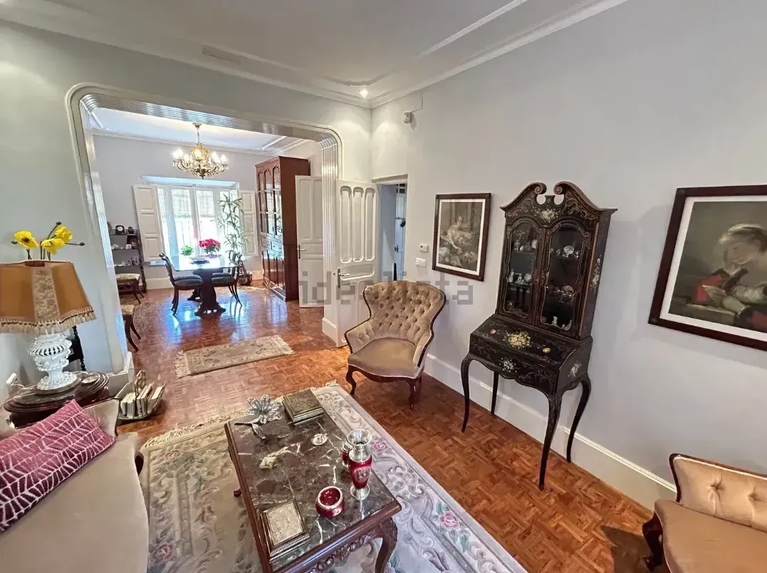 Elegante sala de estar con muebles antiguos, obras de arte y vista al comedor.