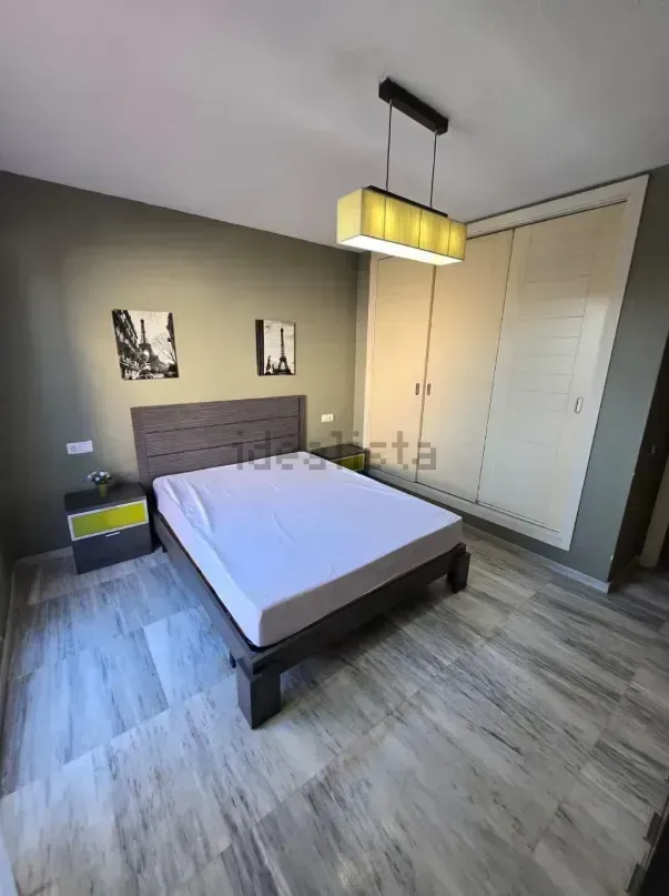 Dormitorio con cama, mesita de noche, armario y lámpara de techo. 