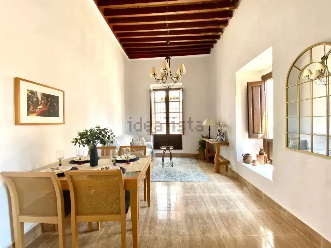 Comedor con techo de madera, mesa puesta para seis y ventana arqueada.