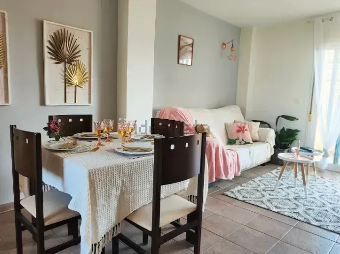Comedor con mesa puesta para comer, sofá, alfombra, mesa de café pequeña.