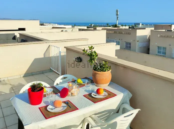 Mesa en la azotea preparada para comer, con vistas al océano azul.