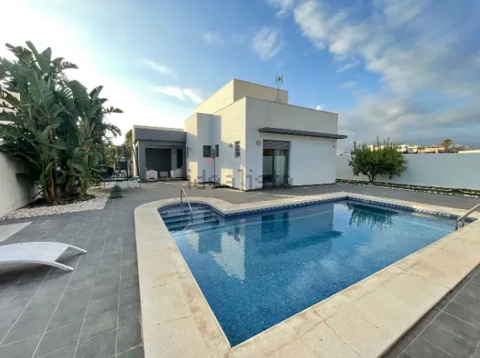Moderna casa blanca con piscina en un entorno exterior soleado.