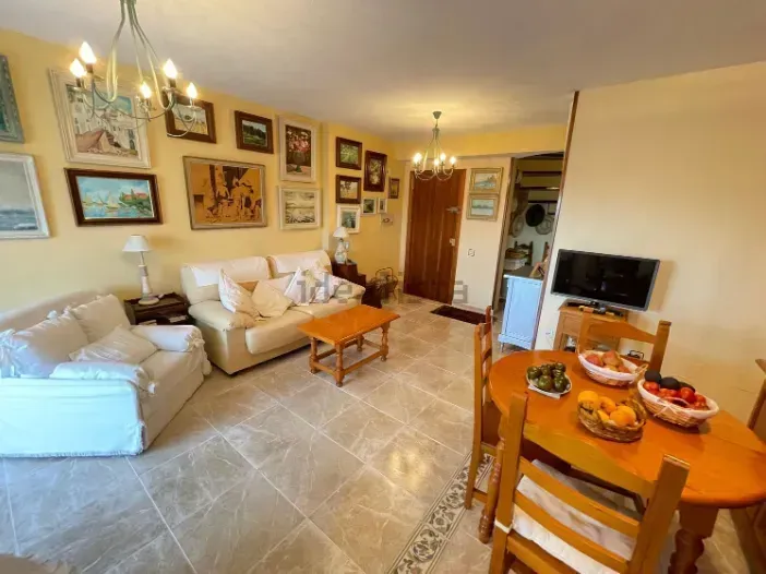 Acogedora sala de estar con sofás de colores claros, una mesa de centro de madera y una mesa de comedor.