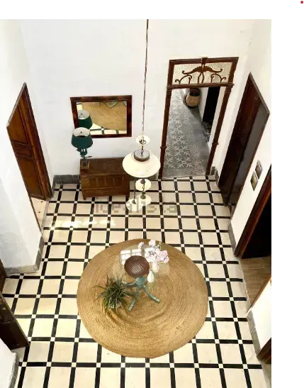 Vista de un vestíbulo con suelo a cuadros blancos y negros, una mesa redonda y varias puertas.