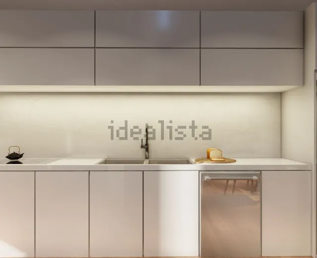 Cocina blanca moderna con gabinetes superiores, lavavajillas de acero inoxidable y fregadero.