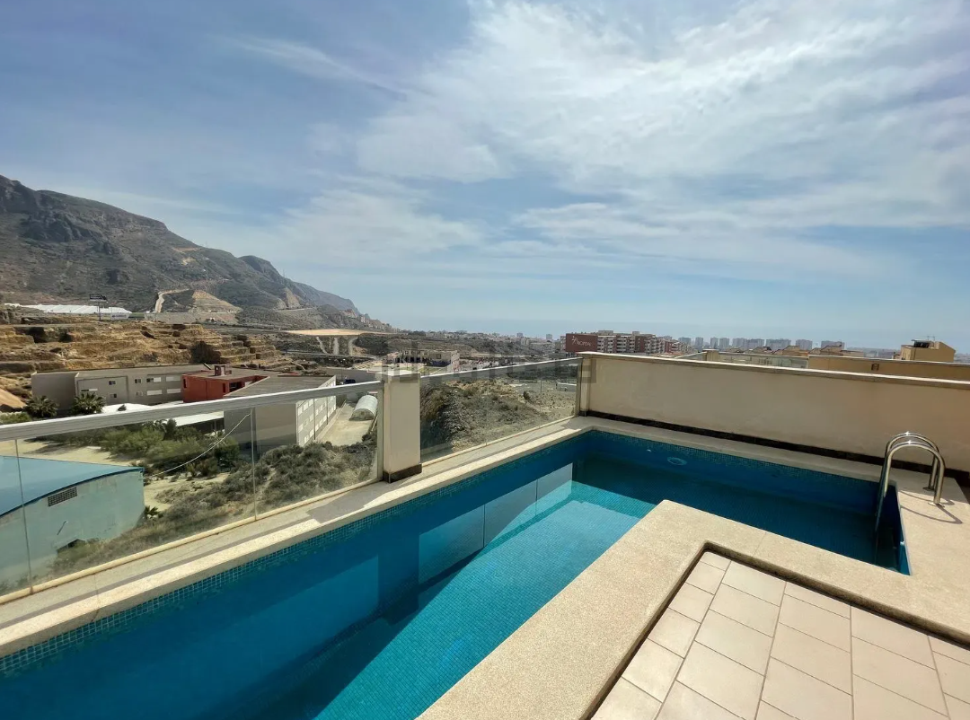 Casa moderna con piscina y terraza; cielo azul y exterior soleado.