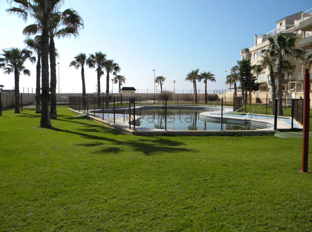 Casa moderna con piscina y terraza; cielo azul y exterior soleado.