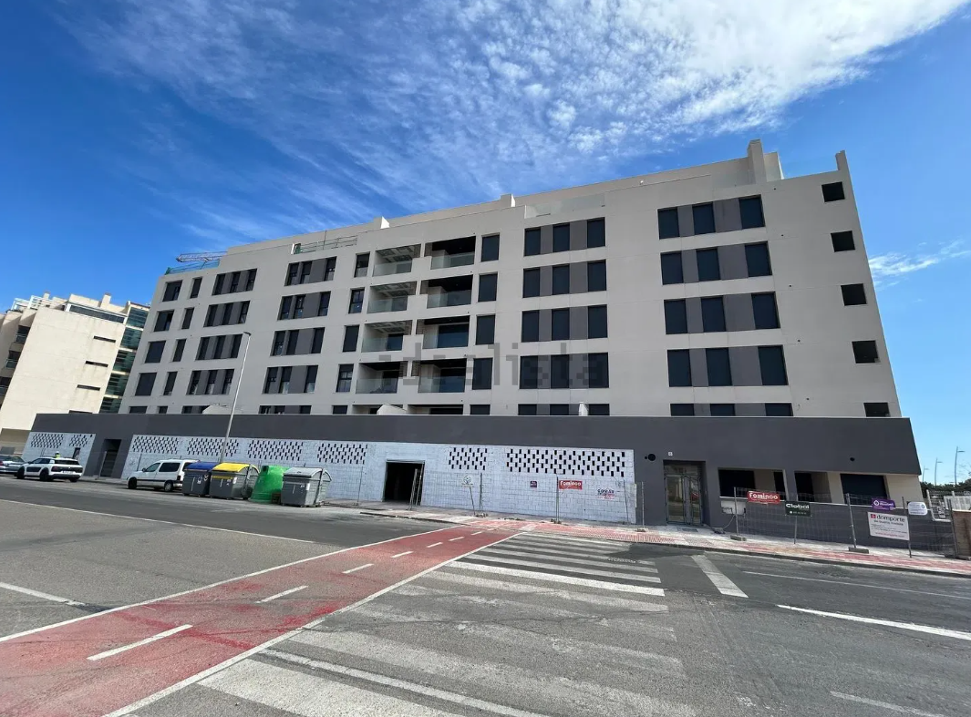Habitación vacía con suelo de madera, ventanal con balcón y puerta de entrada.