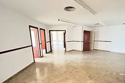 Sala de estar con sofás florales azules, mesa de centro de cristal y comedor visible al fondo.