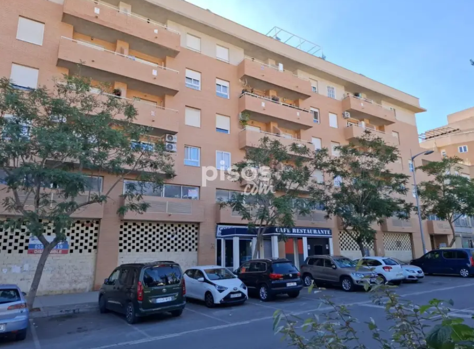 Sala de estar con sofás florales azules, mesa de centro de cristal y comedor visible al fondo.