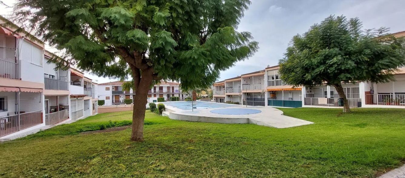 Sala de estar con sofás florales azules, mesa de centro de cristal y comedor visible al fondo.