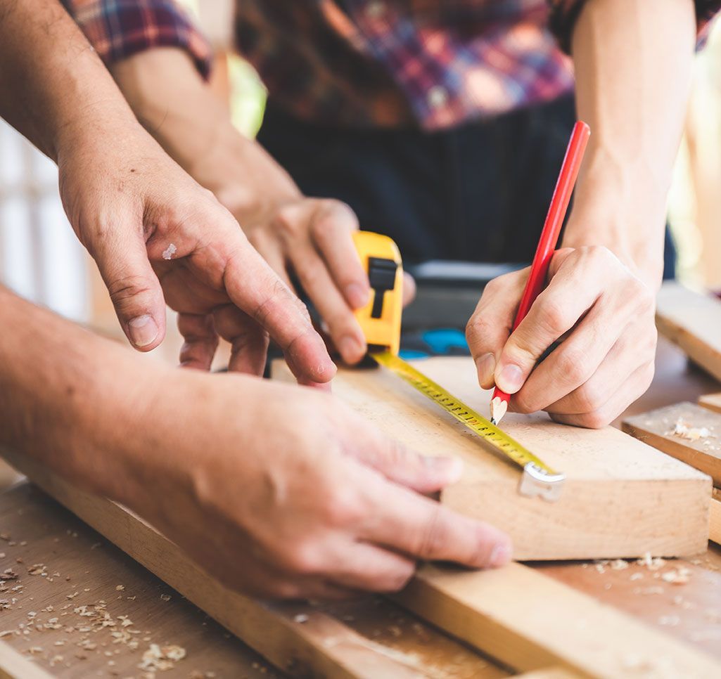 Deux personnes qui mesurent un morceau de bois