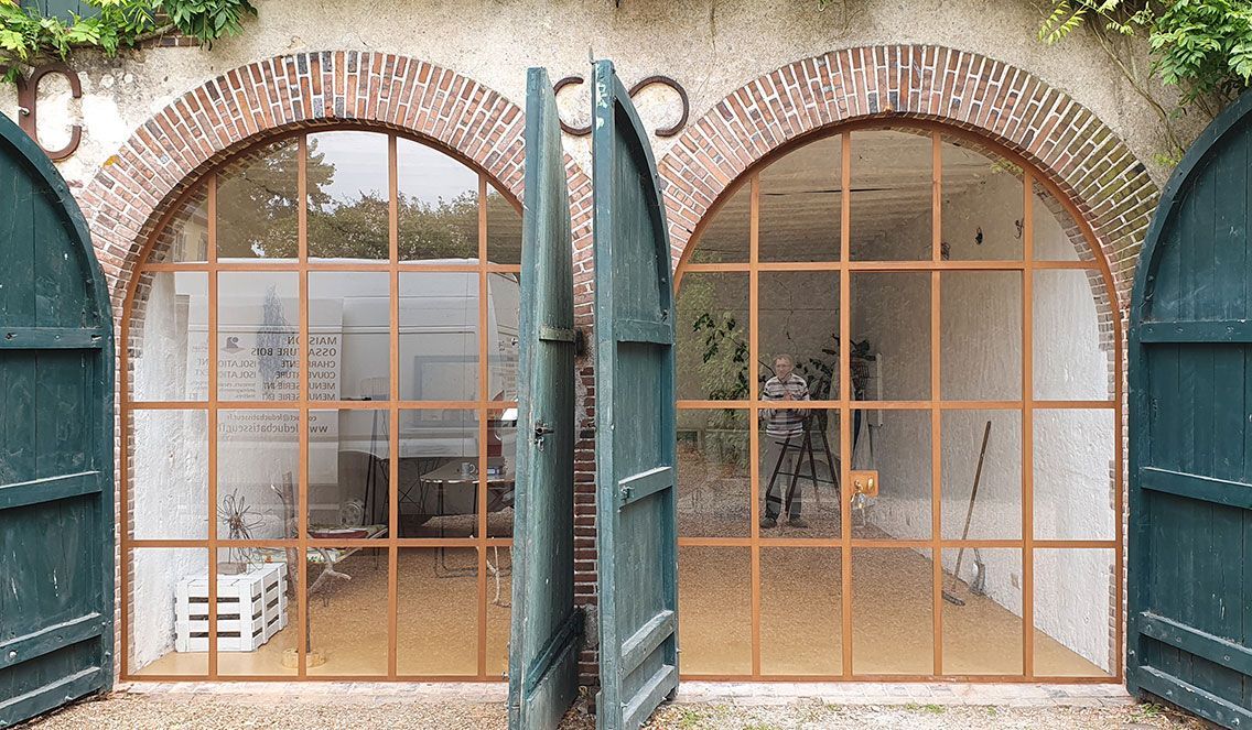 Double fenêtre en bois et en arc avec des volets vert