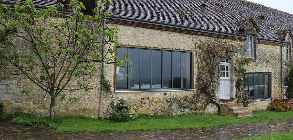 Maison en pierre avec de grandes fenêtres en aluminium