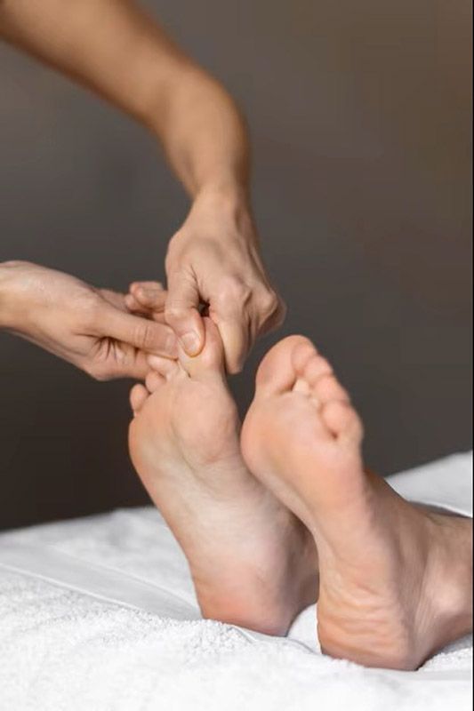Dos mujeres se ejercitan en reformers de Pilates en un estudio. Se sientan con las piernas extendidas y las manos sujetas a las correas.