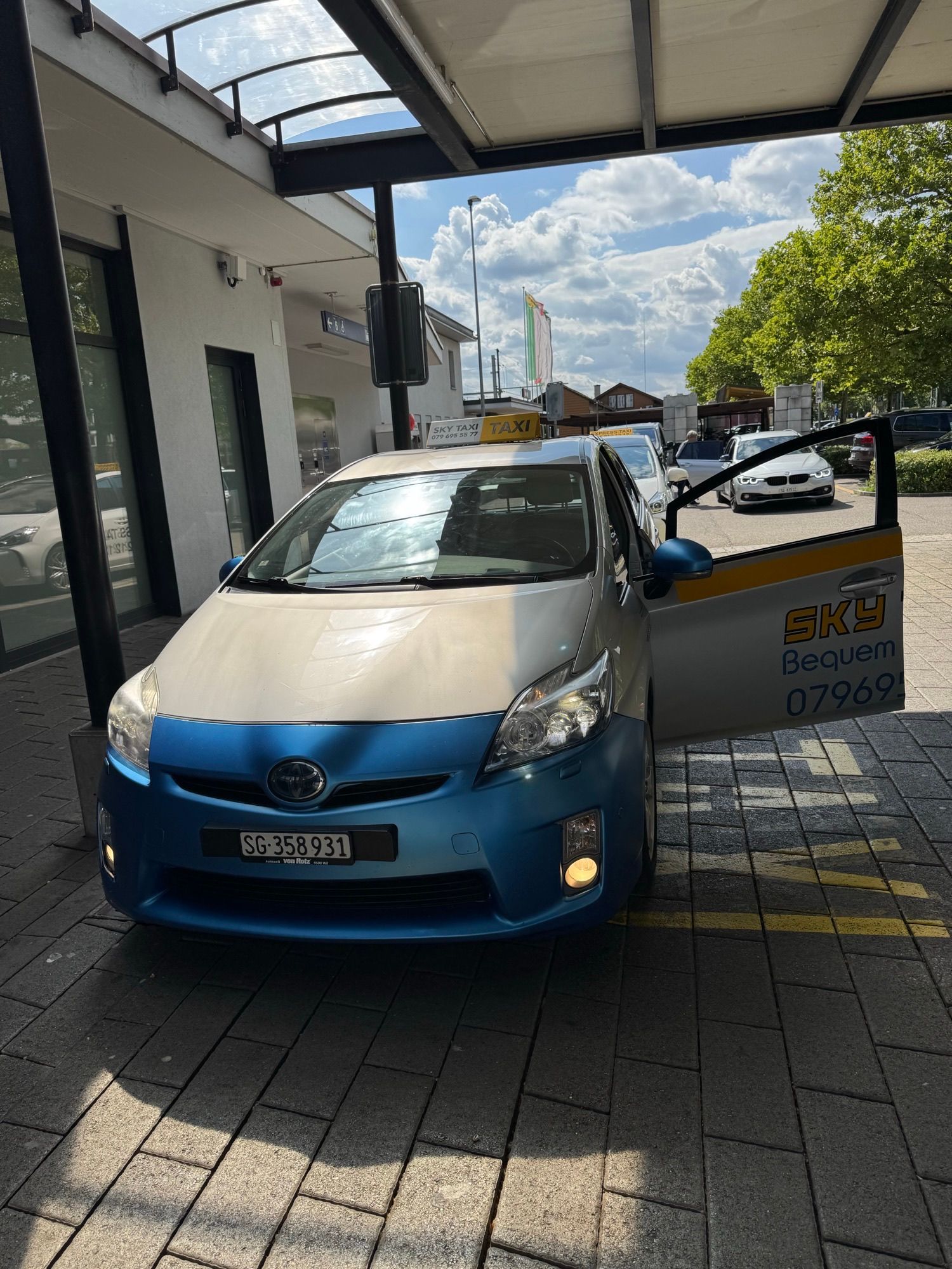 Ein blau-weißer Toyota Prius steht auf einem Parkplatz.