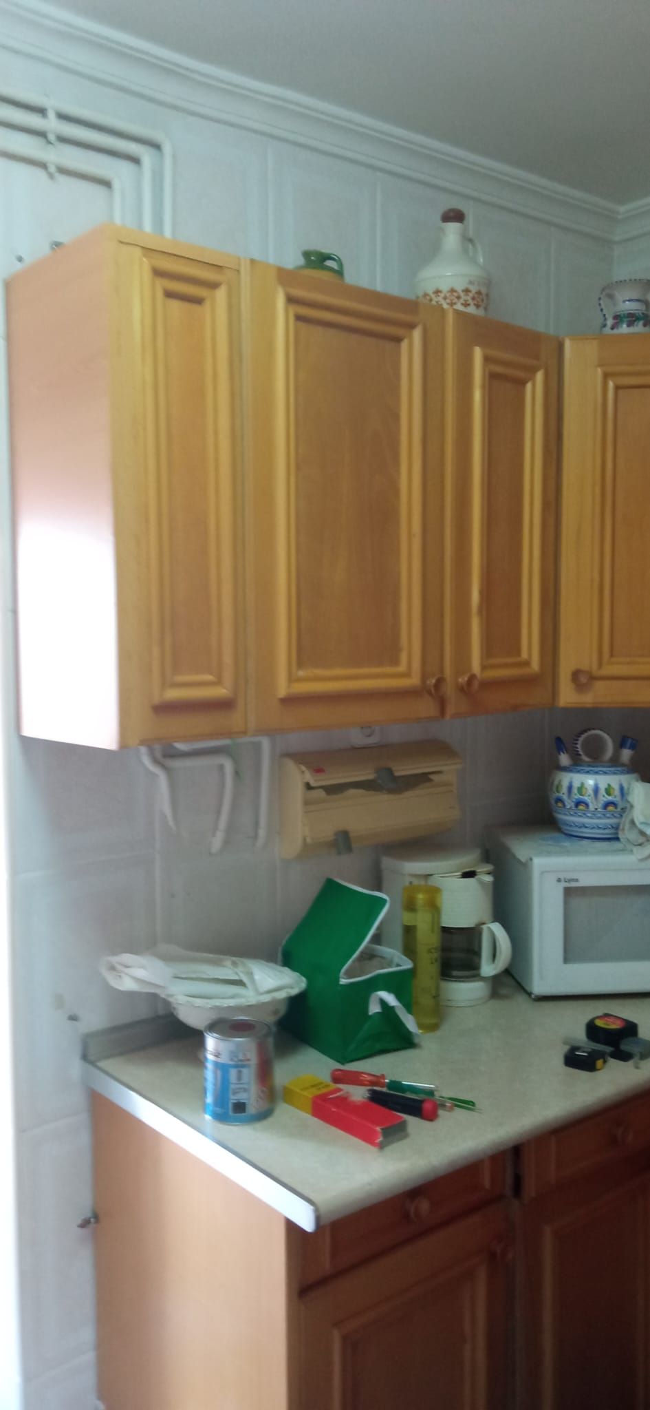 Una cocina con gabinetes de madera, un microondas y una cafetera.