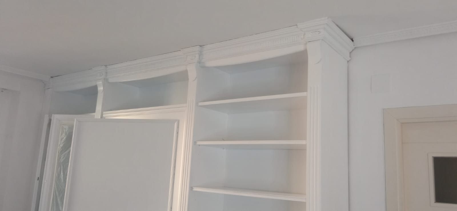 Una habitación con muchos estantes y una puerta.