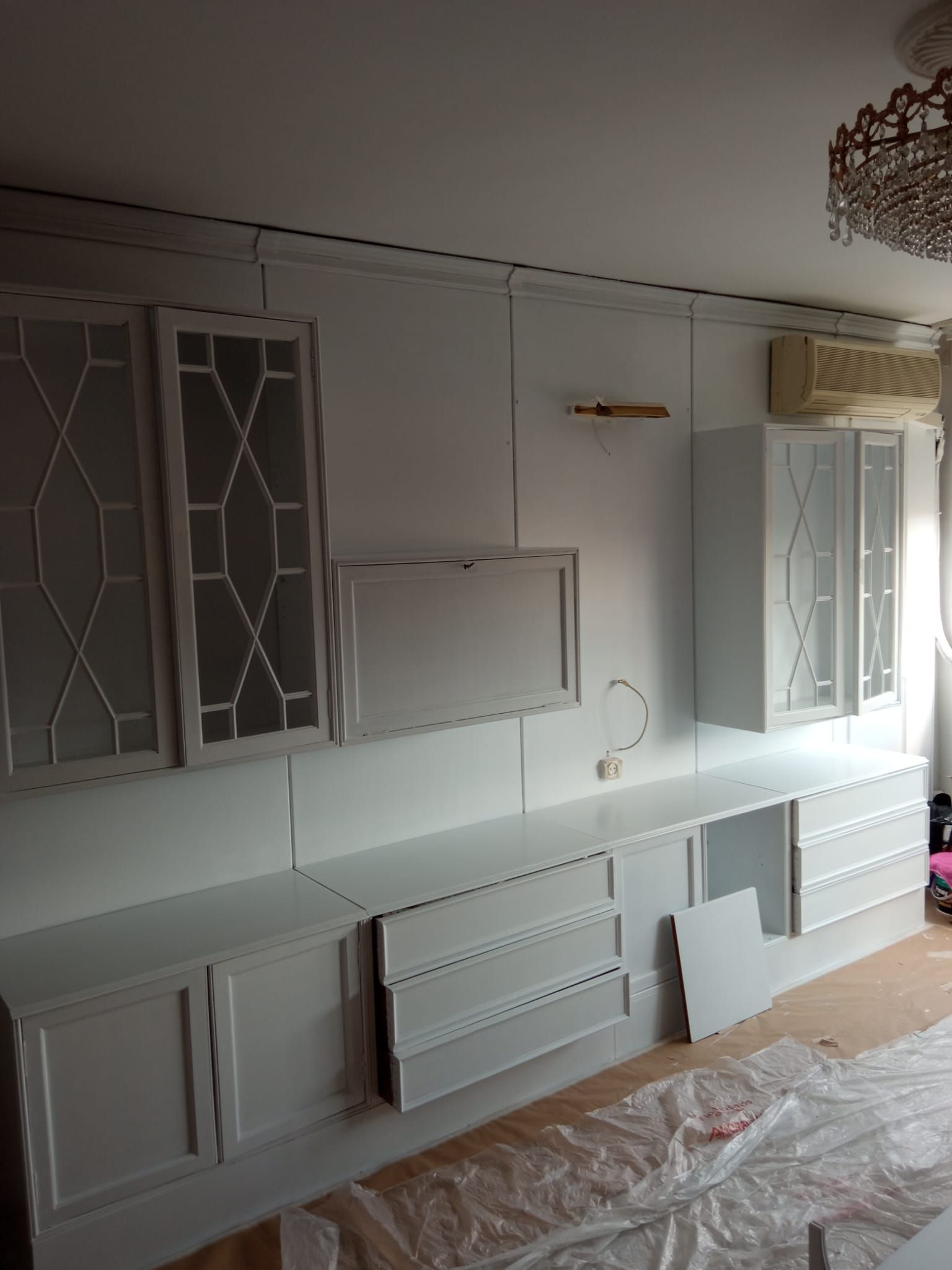 Una sala de estar con armarios y cajones blancos y una lámpara de araña.