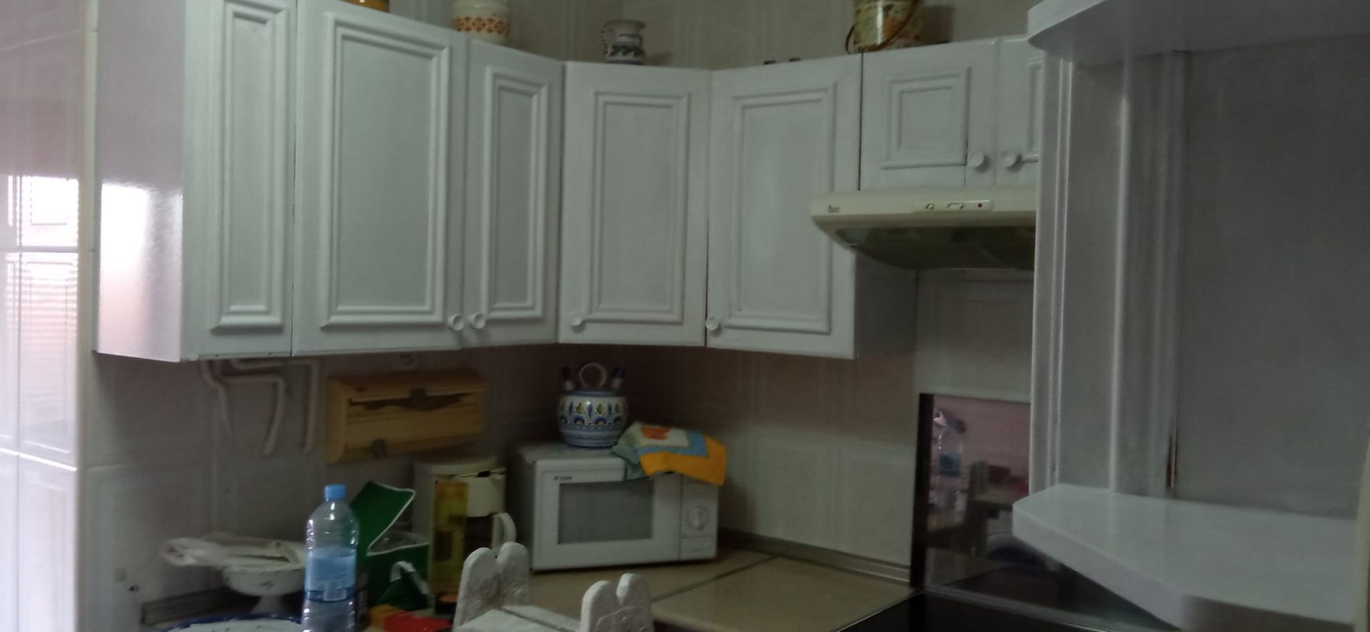 Una cocina con gabinetes blancos, un microondas y un fregadero.