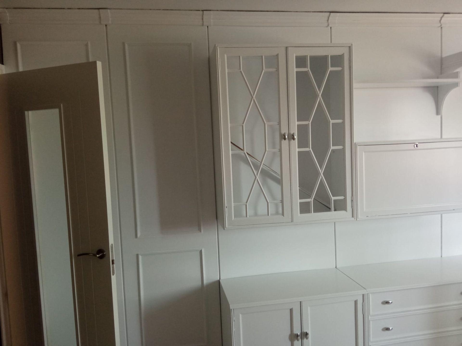 Una habitación con armarios y cajones blancos y un espejo.