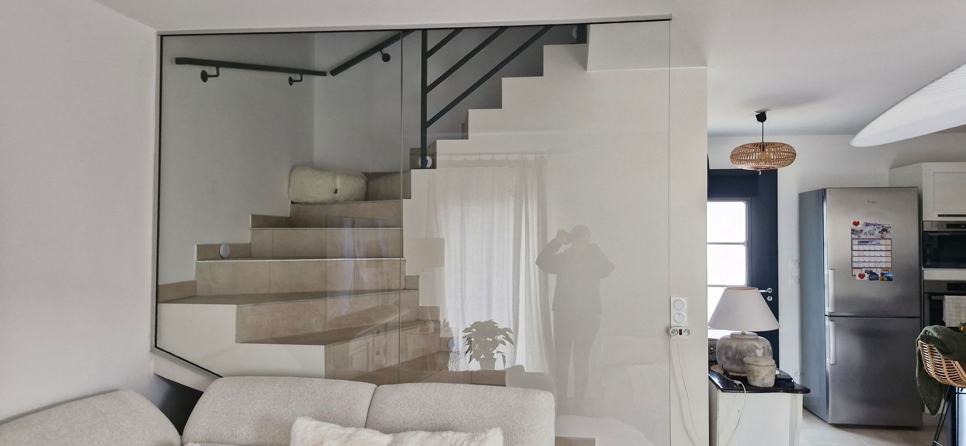 Vue intérieure avec escalier, paroi vitrée et porte ouverte sur la cuisine équipée