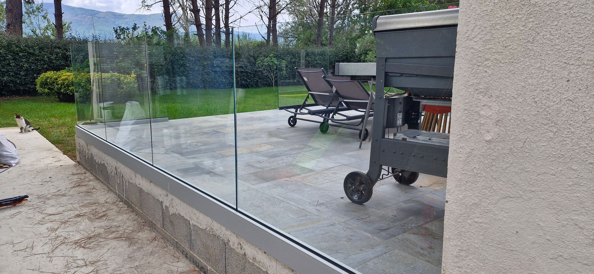 Une terrasse avec des parois vitrées et un barbecue