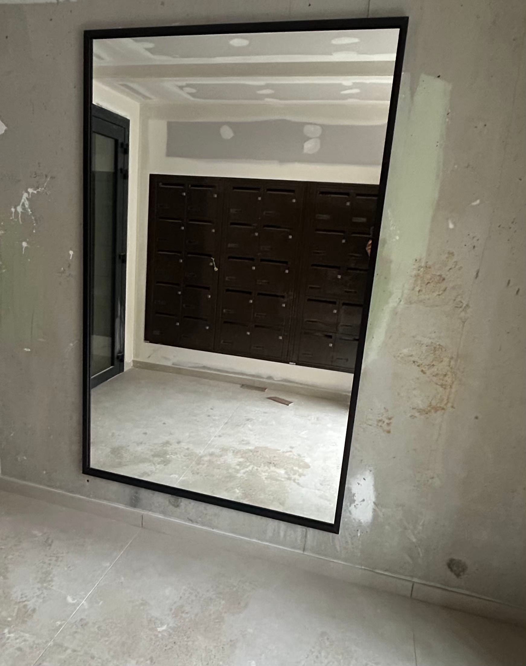 Miroir dans une pièce en construction, reflétant un intérieur aux boiseries sombres et aux murs inachevés