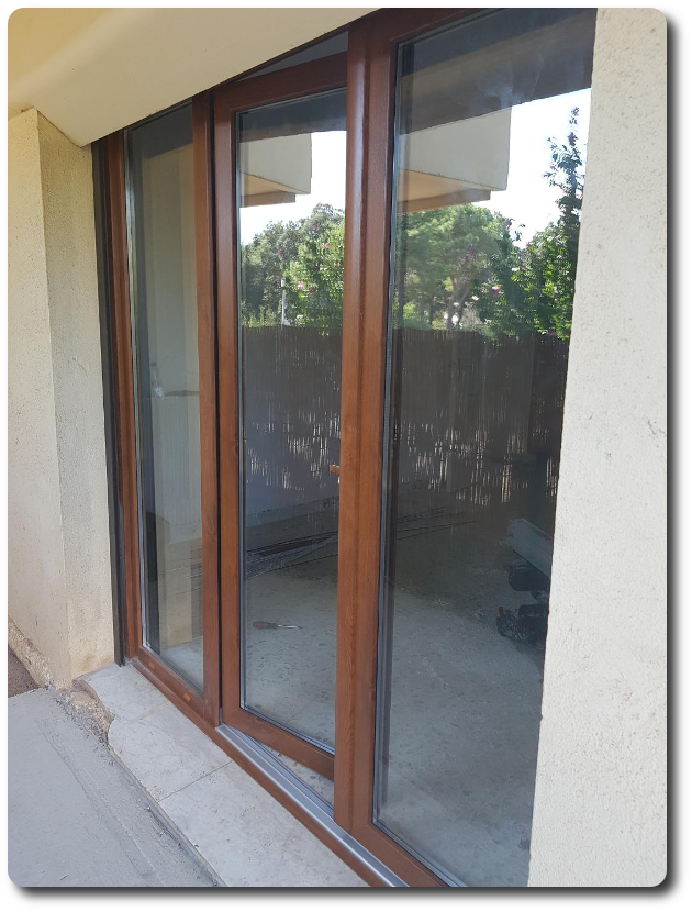 Baie vitrée avec menuiseries en bois, composée de larges surfaces vitrées offrant une ouverture directe sur un espace extérieur.