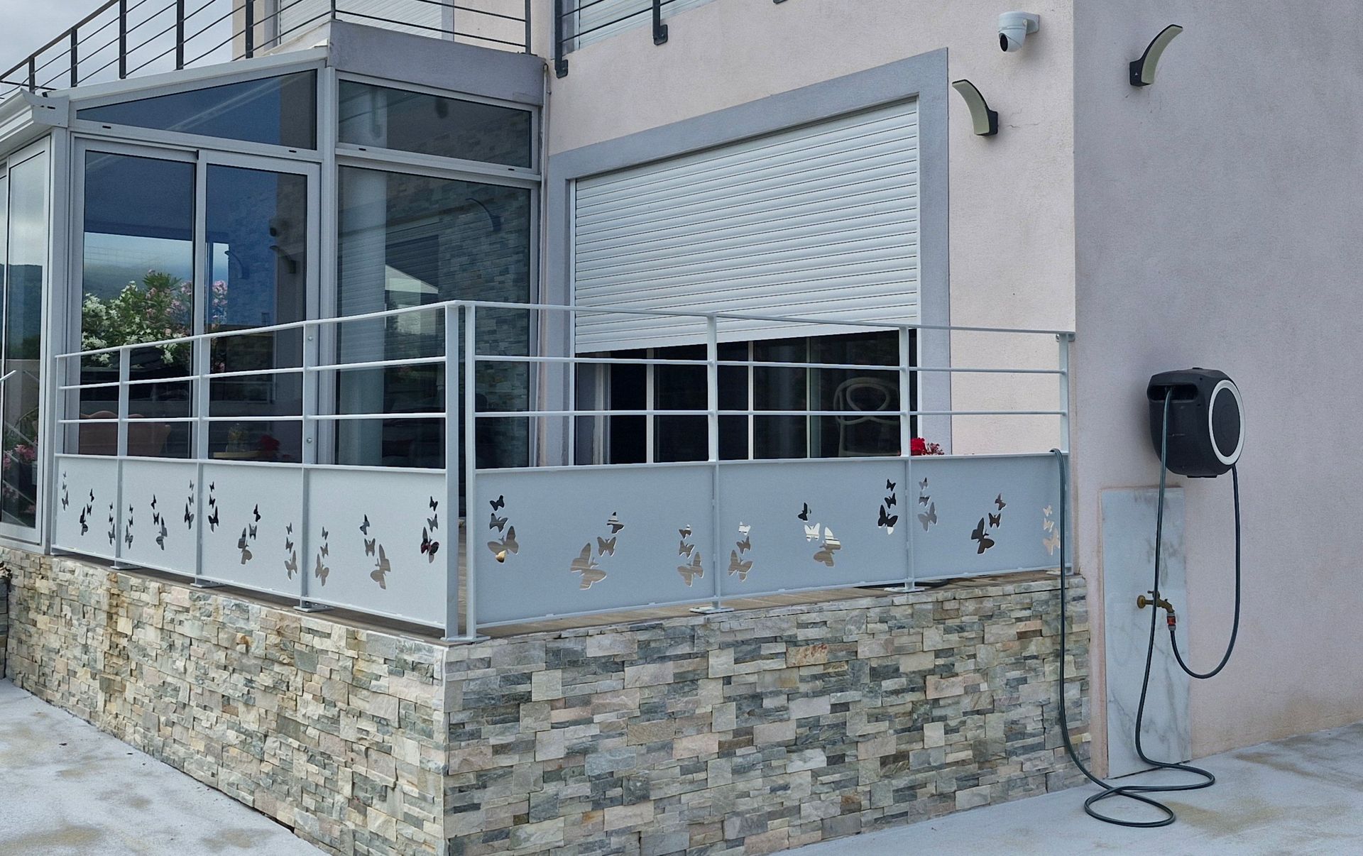 Vue extérieure d'un bâtiment moderne avec un patio vitré, une balustrade métallique décorative