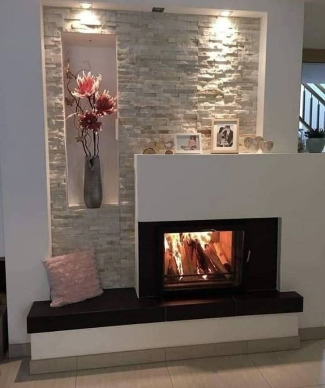 Ouverture vitrée rectangulaire intégrée dans un mur, avec un foyer visible en dessous et des éléments décoratifs autour.