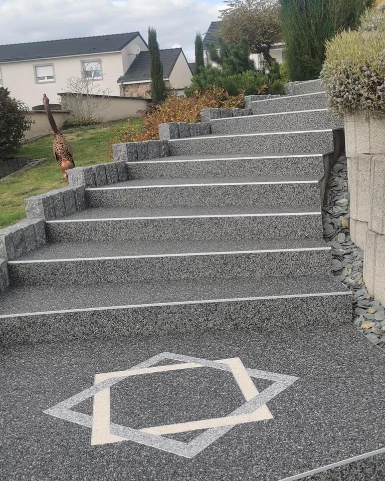 Escalier extérieur en pierre grise menant à une maison, avec une forme décorative à la base.