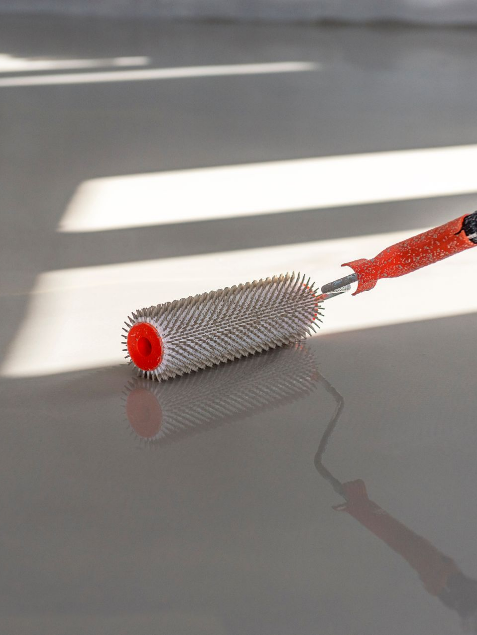 Sol de garage poli et moucheté avec une voiture garée à l'intérieur et la porte du garage ouverte.