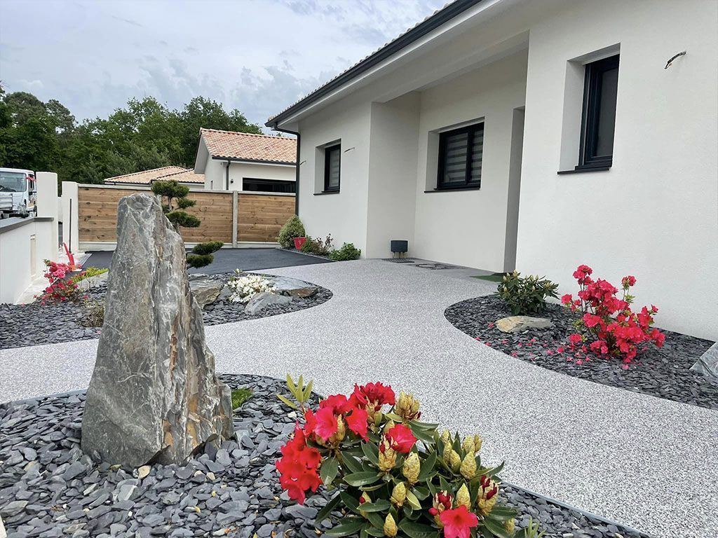 Patio en béton avec balustrade en bois et volets verts, adossé à un village à flanc de colline.