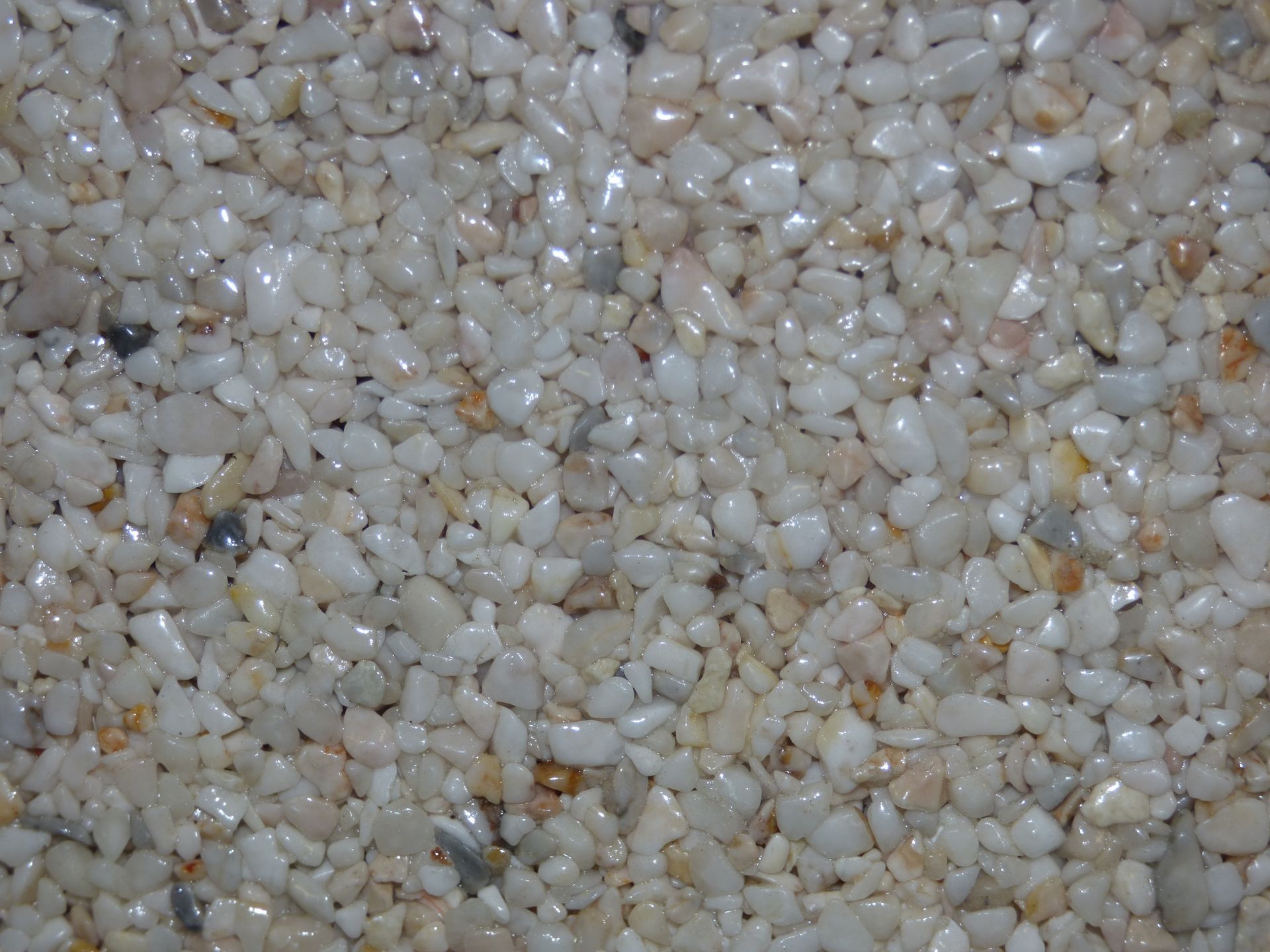 Gros plan de petits cailloux de couleur claire collés ensemble, peut-être une surface de sol.