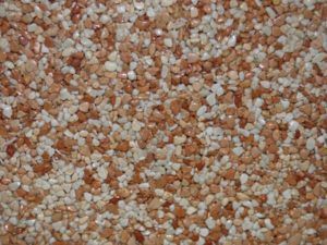 Gros plan d'une surface texturée comportant de petites pierres tachetées, brun rougeâtre et beiges.