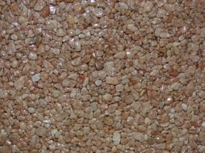 Vue rapprochée d'une surface d'agrégat brun rougeâtre avec de petites pierres arrondies et une texture légèrement brillante.